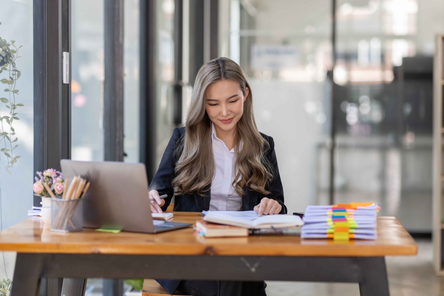 A woman bookkeeper at a desk with a laptop, showing what does a bookkeeper do.